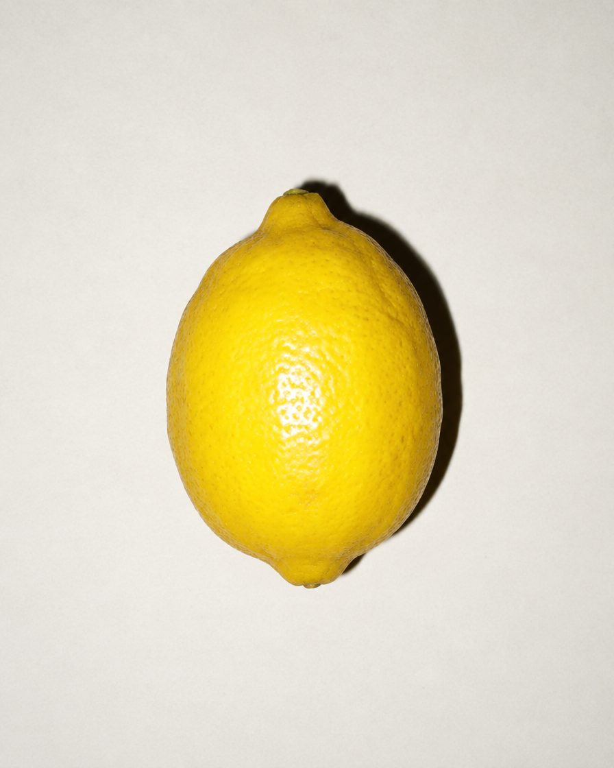 One lemon under harsh flash with a hard shadow